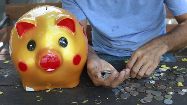 亚洲年轻人用存钱罐数硬币到手里，存钱的概念视频素材