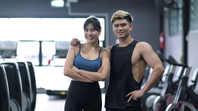 肖像年轻的亚洲男人和女人有吸引力的健身夫妇站在一起后，在现代交叉健身馆的慢动作镜头。视频下载