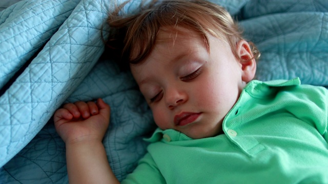 小男孩躺在床上睡觉。一岁的婴儿睡着了视频素材