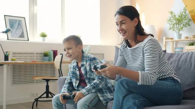 母亲和活跃的男孩在公寓玩电子游戏一起玩视频素材