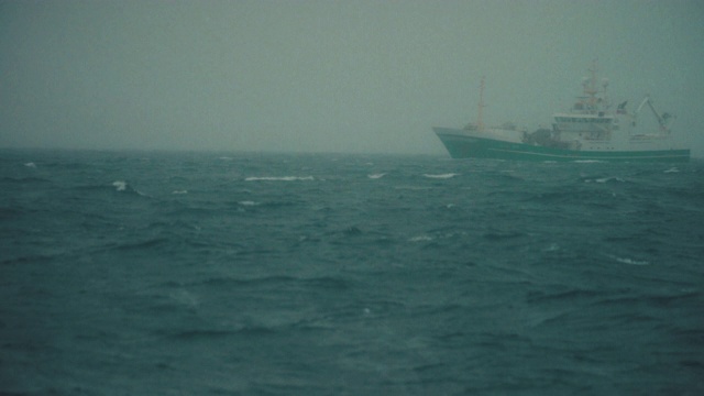 渔船在薄雾中捕鱼:冬天波涛汹涌的海面视频素材