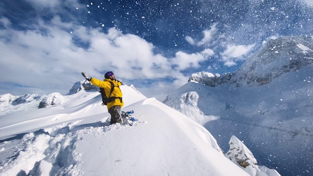 充满喜悦的滑雪板站在山顶的雪山在一个阳光明媚的冬日视频素材