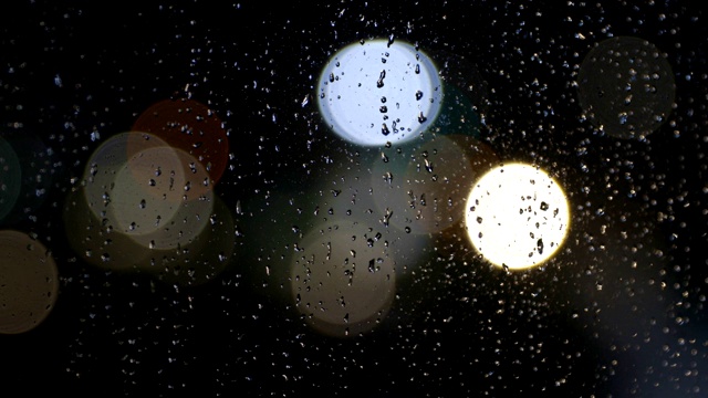 散焦灯光下的雨打在窗户上视频素材