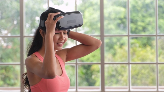 亚洲女性佩戴虚拟现实，选择方案在家训练。可穿戴技术生活方式视频素材