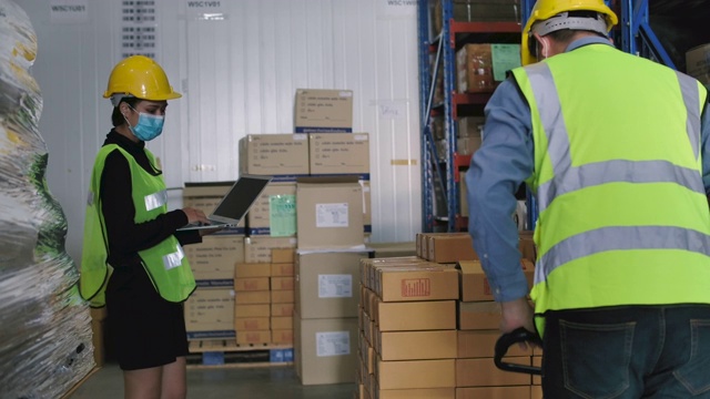 仓库员工用托盘千斤顶将一板条箱的箱子搬开。视频素材