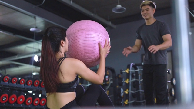亚洲夫妇练习与俄罗斯扭转举行瑜伽球隐喻健身和锻炼概念运动健康生活方式肌肉身体和健康教练协助训练视频下载