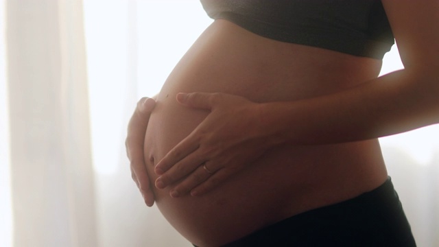 女人触摸怀孕的肚子。女性爱抚着9个月的肚子视频素材