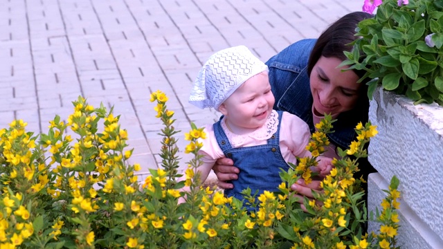 妈妈带着女儿在公园里散步，抱着她看花。视频下载