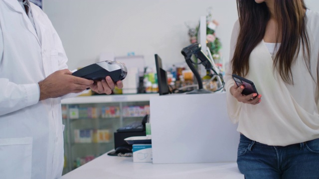 亚裔华人女顾客在药店收银员用信用卡支付她的处方药视频素材