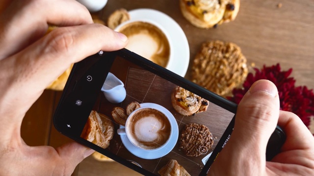 男人的手用现代智能手机拍照热咖啡杯与新鲜面包视频下载
