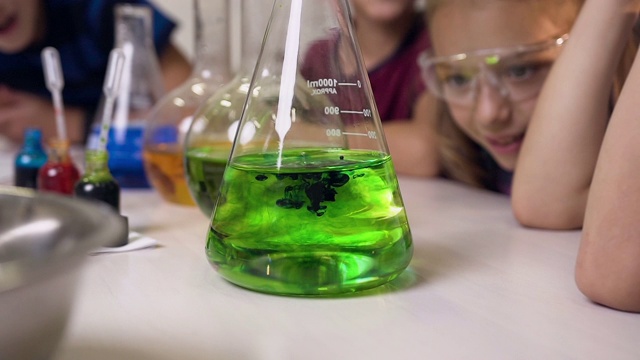 关闭了。实验室工作人员将化学液体与水混合在玻璃烧瓶中，向孩子们展示化学反应是如何以颜色进行的视频下载
