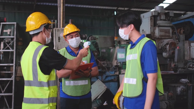 技术员工作人员在工作结束后戴上面罩配合使用红外温度计测量温度以筛选工厂工人视频下载