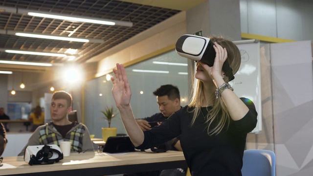 年轻的白人商务女性戴着虚拟现实眼镜在办公室工作视频素材