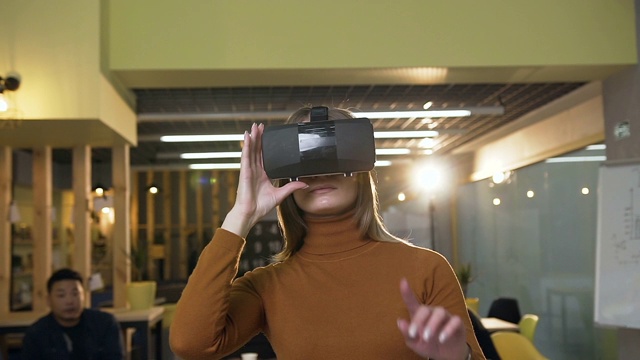 戴着虚拟现实眼镜在办公室工作的时尚女性视频素材
