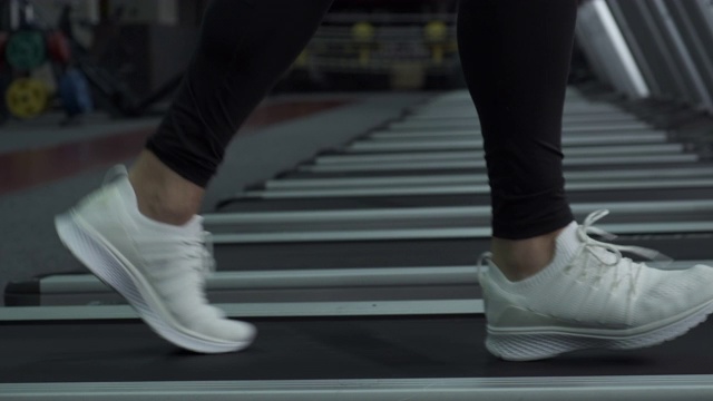 穿着运动鞋在跑步机上跑步的男人的脚视频素材