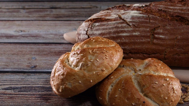 特写美味的有机面包和黑麦面包与谷物和木勺在桌子上视频素材