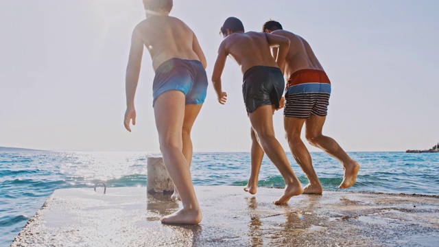 SLO MO Man和两个男孩从码头跳进海里视频下载
