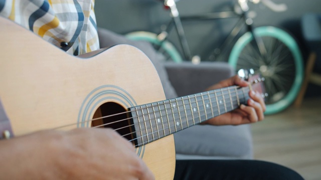 男性手在家里拿着乐器弹吉他的特写视频素材