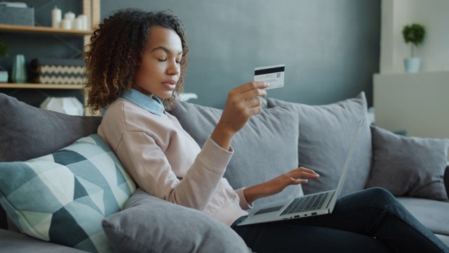 非裔美国妇女用信用卡和笔记本电脑在网上进行无现金支付视频素材