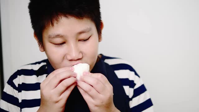 亚洲男孩穿着围裙在白墙上剥煮鸡蛋。视频素材