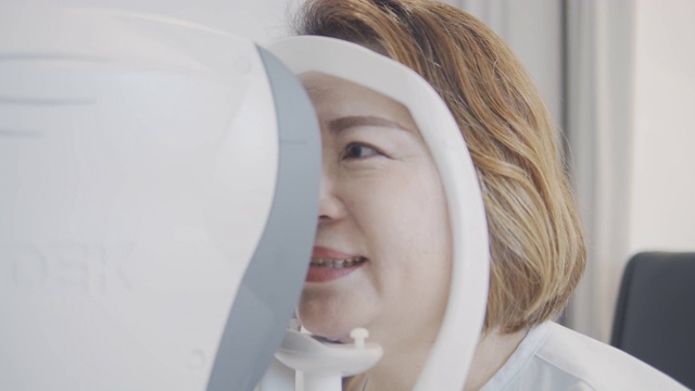 亚洲资深女性病人在验光店由医生检查眼睛。使用自动折射仪、摄影仪、试验架、断线、视力表、监测图和眼检炬。一位老年男性的眼部症状。医学教育、医疗保健。视频素材