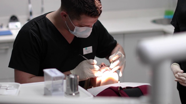 牙科医生戴着防护面罩准备给病人治疗的牙医视频下载