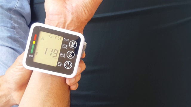 在家里用便携式设备测量你的血压来检查你的健康状况。该装置显示高压值。视频素材
