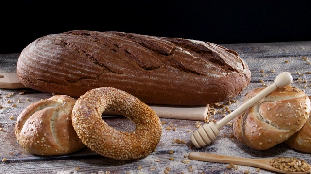 面包师把新鲜的有机黑麦面包和小圆面包、百吉饼和面粉装饰在切板上视频素材