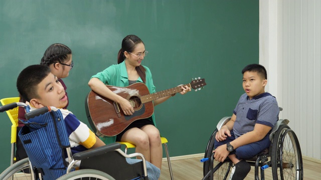 老师在教室里弹吉他陪着残疾儿童，非常开心视频素材