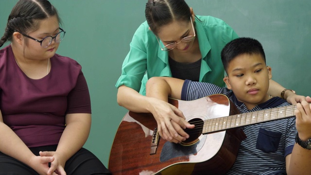 老师在教室里教残疾儿童吉他，非常开心视频素材