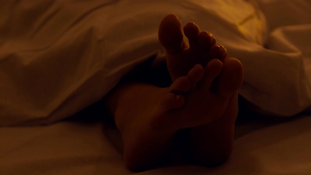 女人的脚在毯子下面的特写，女孩睡在床上视频素材