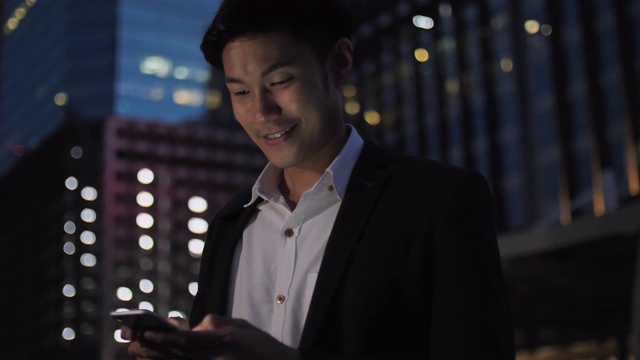 漂亮的亚洲商人在晚上下班后使用电话视频下载