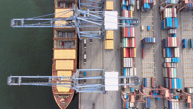 4k拍摄的无人机，一艘货轮坐在真正的工作在泰国港码头起重机吊杆下降到位置卸货集装箱。视频素材