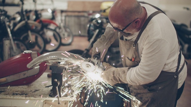 一个成熟的男人在摩托车修理店使用磨床视频素材