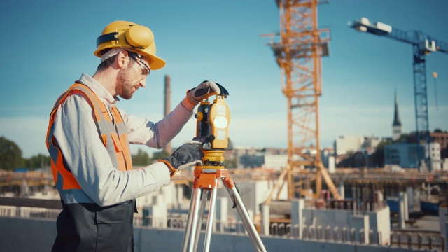 建筑工人使用经纬仪测量光学仪器在施工现场测量水平面和垂直面角度。戴安全帽的工人正在为大楼做投影。视频素材