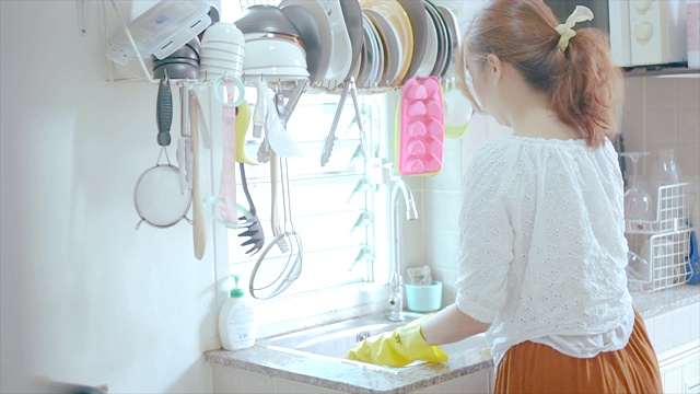 年轻女子在洗盘子。视频素材