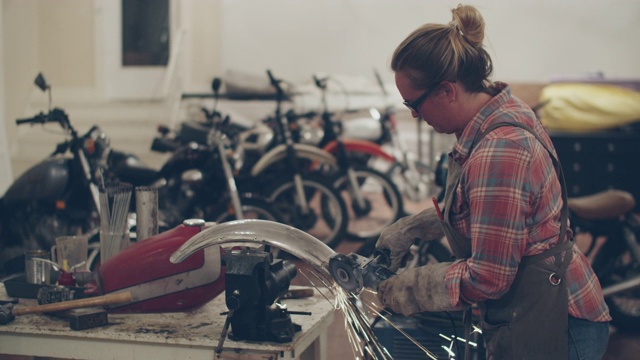 一个年轻女子在修理厂修摩托车视频素材