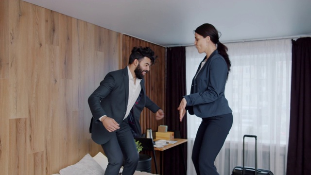 快乐的多民族夫妇，男人和女人跳舞在酒店的床上一起玩视频素材