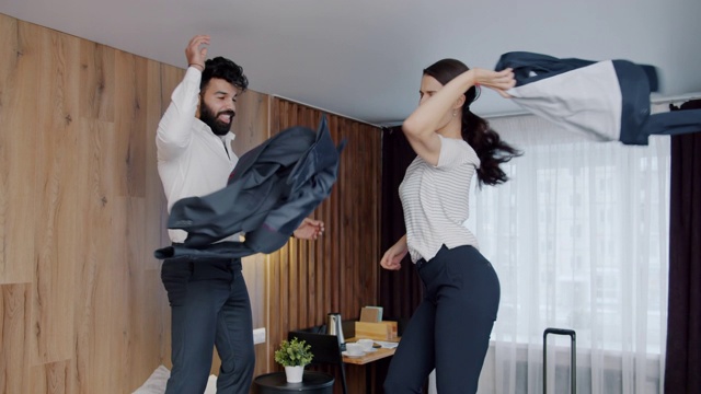 快乐的年轻人丈夫和妻子跳舞在酒店的床上脱衣玩视频素材