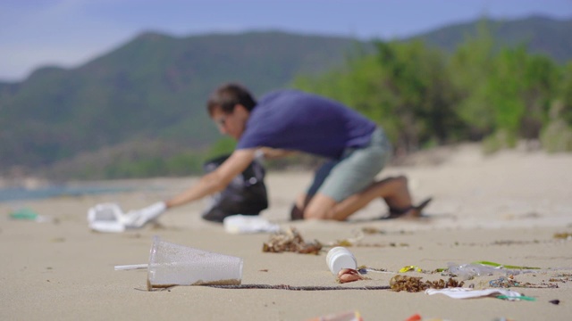 戴手套的人在海滩上收集塑料垃圾。沙滩上的垃圾问题是由人为污染造成的。环保运动，清洁环境。生态志愿服务概念视频素材
