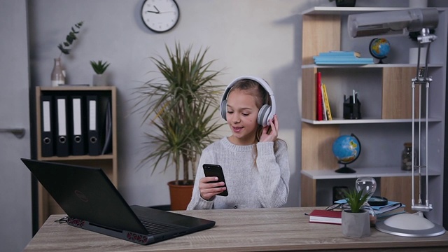 正面的观点兴高采烈的好看的微笑15岁女孩听煽动性的音乐在她的耳机在家里视频素材