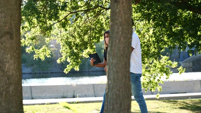 戴面具的女学生在校园里的一棵树下学习视频下载
