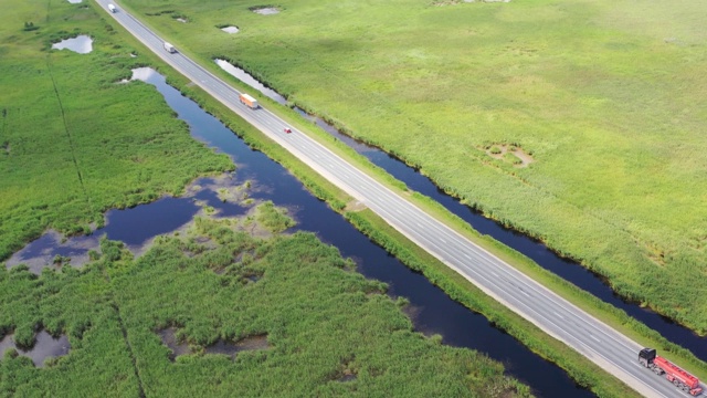 鸟瞰图的快速卡车在乡村和沼泽地形的道路上视频素材