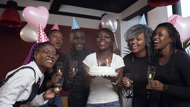 快乐迷人的年轻非洲妇女吹蜡烛的生日蛋糕周围的朋友视频素材