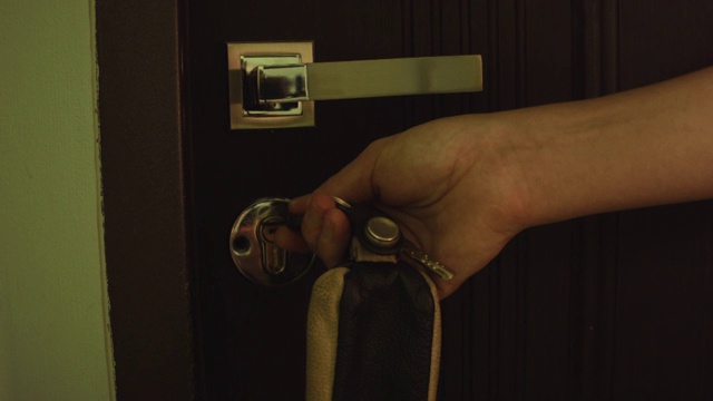 年轻的白人女子用公寓的钥匙打开了前门。键和手的特写。视频下载