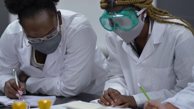 多民族学生戴着口罩在实验室工作视频素材