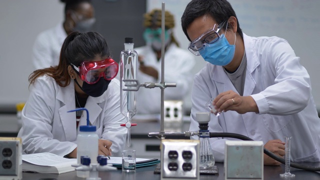 多民族学生戴着口罩在实验室工作视频素材