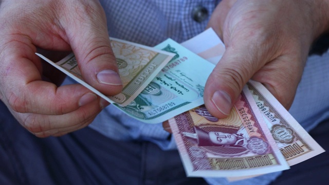 一名穿着商务衬衫的男子在数一种叫图格里克的蒙古货币。各种钞票视频下载
