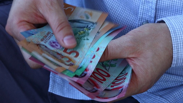 一名穿着商务衬衫的男子在数新西兰币。很多不同的美元视频下载