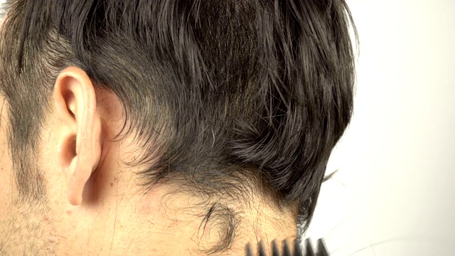 理发师用理发器剪头发的特写。男士用电动剃须刀理发。在理发店理发。理发师大师给一个年轻人理发。视频素材
